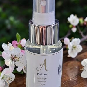 Perfume bottle with clear cap and metallic collar on a wooden table, surrounded by white blossom petals.