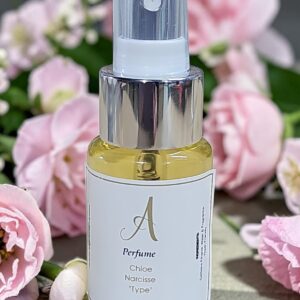 Perfume spray bottle with a silver cap among pink flowers; label reads 'A Perfume Chloe Narcisse Type' (30 ml).