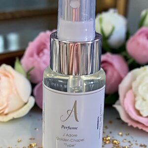 Close-up of a perfume spray bottle with a clear cap, with pink and white roses in the background.