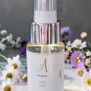 Close-up of a perfume spray bottle labeled 'Daisy Type' with a silver nozzle, surrounded by daisies in a bright setting.